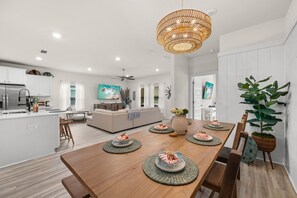 Une cuisine moderne avec un coin repas, un ventilateur de plafond et une grande table à manger dressée avec des assiettes et un vase.