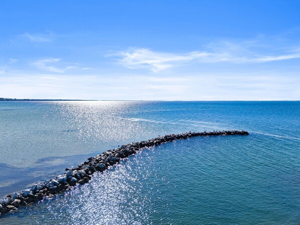 Une mer calme, avec une digue rocheuse qui s’avance dans l’eau.