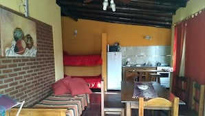 Una habitación funcional con cama, mesa de comedor y kitchenette.