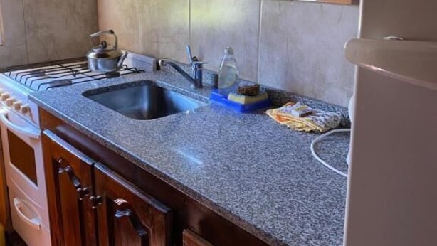 Cocina con un lavamanos doble, estufa y armarios.
