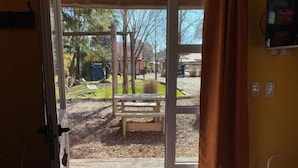 Puerta abierta que da a un espacio exterior con un banco y un parque infantil.