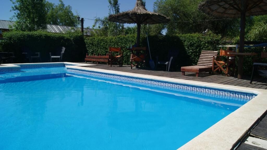 Una piscina amb un pont de fusta, gandules i ombrelles.