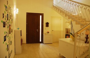 Una escalera con barandilla de hierro forjado que sube a un piso superior, una puerta de madera y una pared con detalles decorativos.