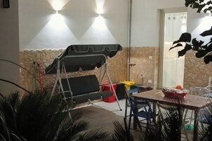 Un espacio patio con un columpio, una mesa y sillas, y un muro de piedra.