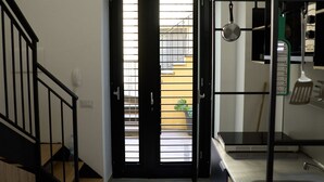 En trappe fører op til en dør, hvorfra der er udsigt til en balkon og et køkken med komfur og redskaber.