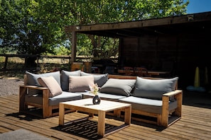 Un área de estar al aire libre con terraza de madera, un sofá y una mesa baja.