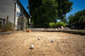 An outdoor area with a dirt ground, a metal fence, and a building with blue windows.