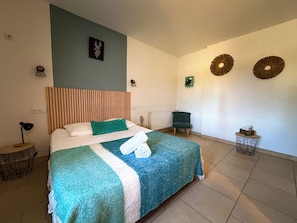 A hotel room with a bed, a chair, a small table, and decorative wall art.