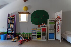 A child's playroom with a bookshelf, toy cars, and storage bins.