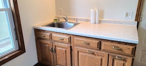 A kitchen with a stainless steel sink, wooden cabinets, and a countertop. - Centrally located 3-bedroom house near beach, boardwalk, brewery, bars, and park (Algoma)