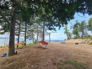 Ein Strand mit einer Hängematte, einer Schaukel und einem Picknicktisch.