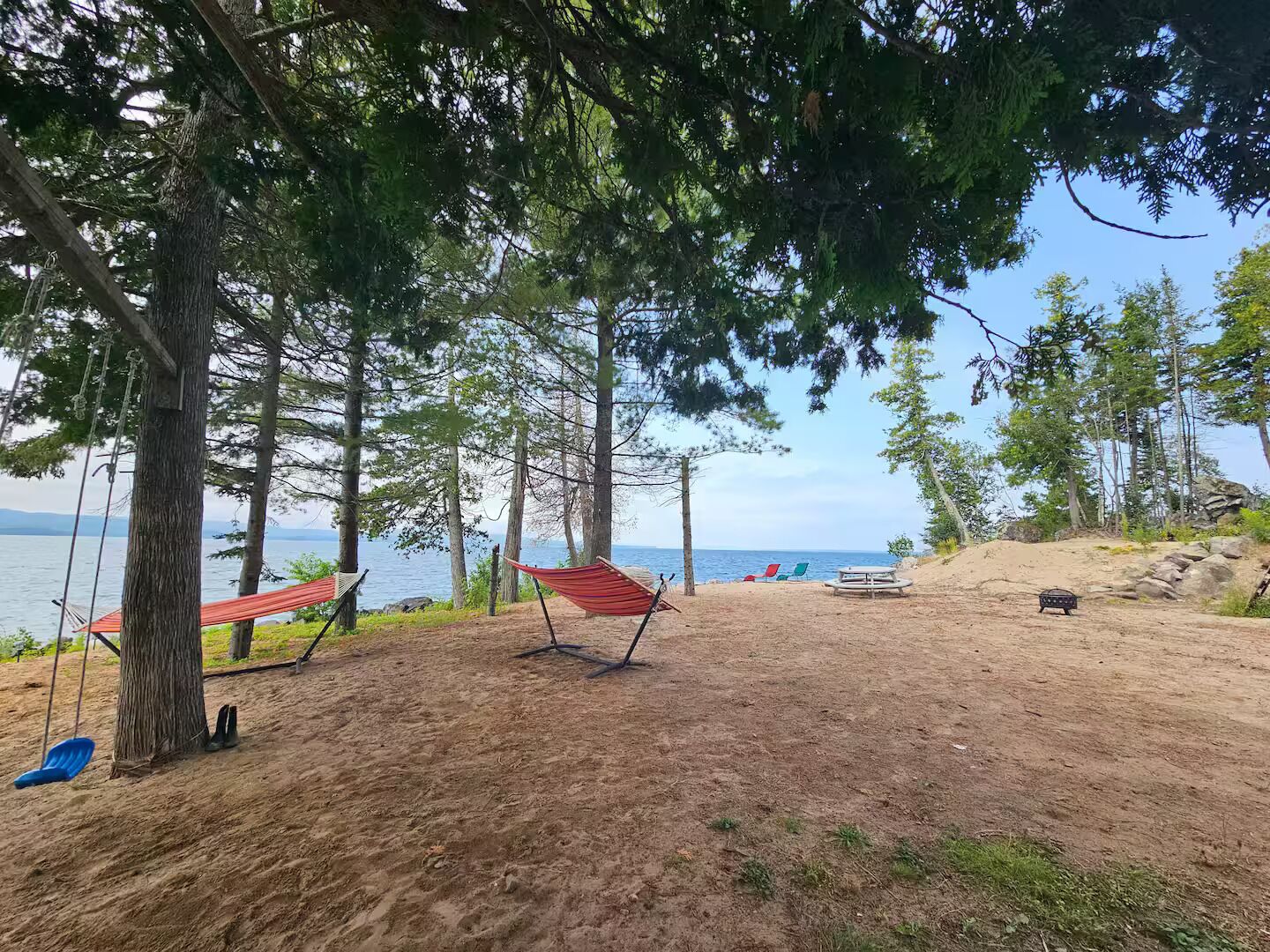 Ein Strand mit einer Hängematte, einer Schaukel und einem Picknicktisch.