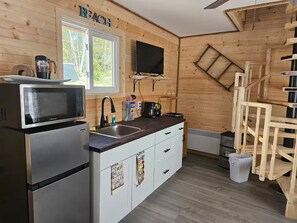 Cocina compacta con microondas, estufa, pileta y alacenas de madera.