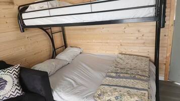 Un letto a castello con un giroletto inferiore e una testiera, adiacente a una parete di legno.