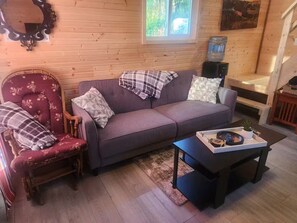 A cozy living room with a sofa, a chair, a coffee table, and a wooden floor.