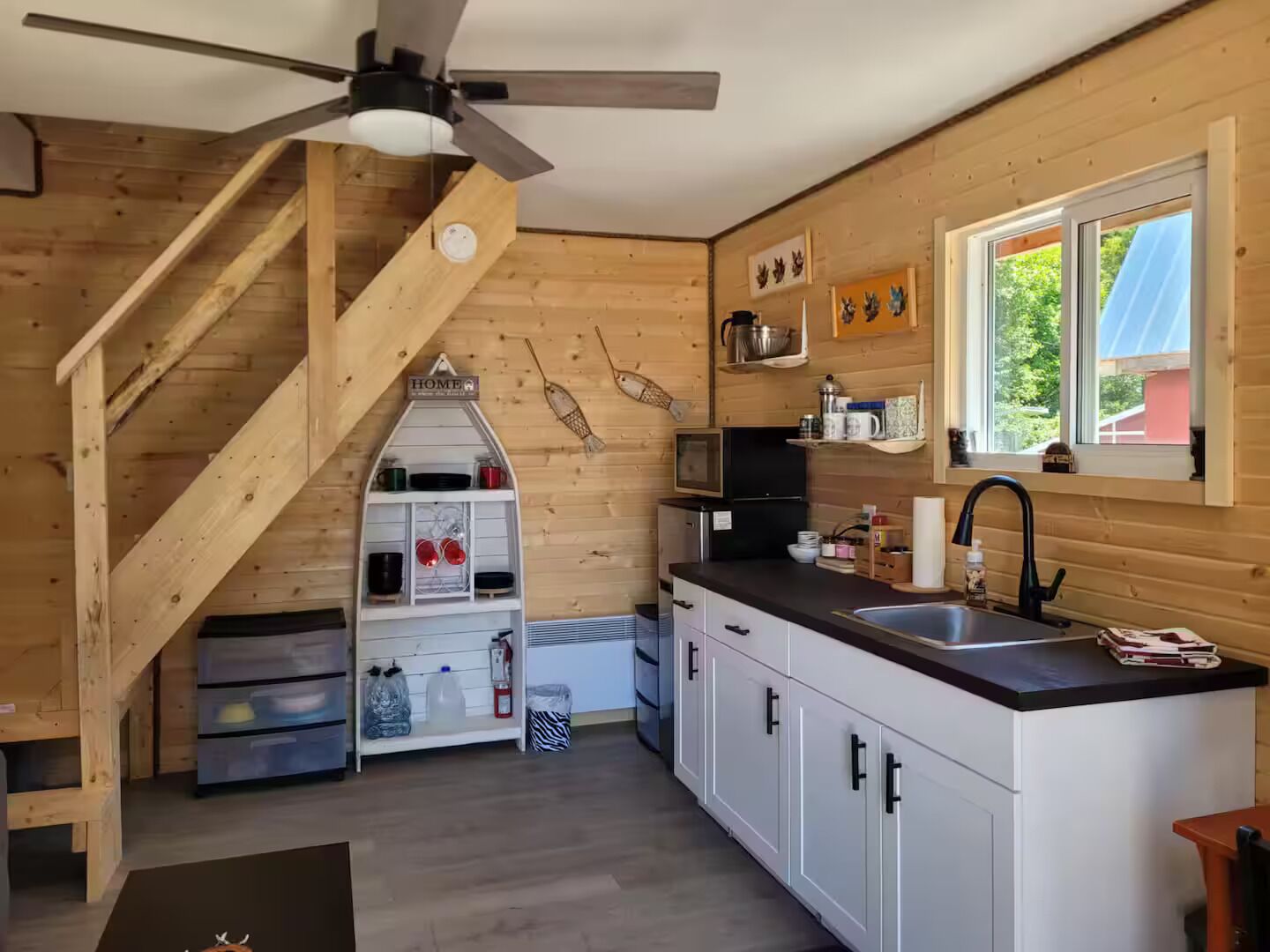 Eine Küche mit Holzwänden, einem Deckenventilator, einem Fenster und einer Treppe.