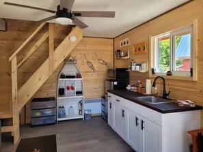 Eine Küche mit Holzwänden, einem Deckenventilator, einem Fenster und einer Treppe.