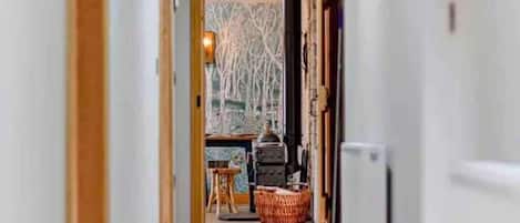 A hallway leading to a room with a fireplace, a table, and a chair.