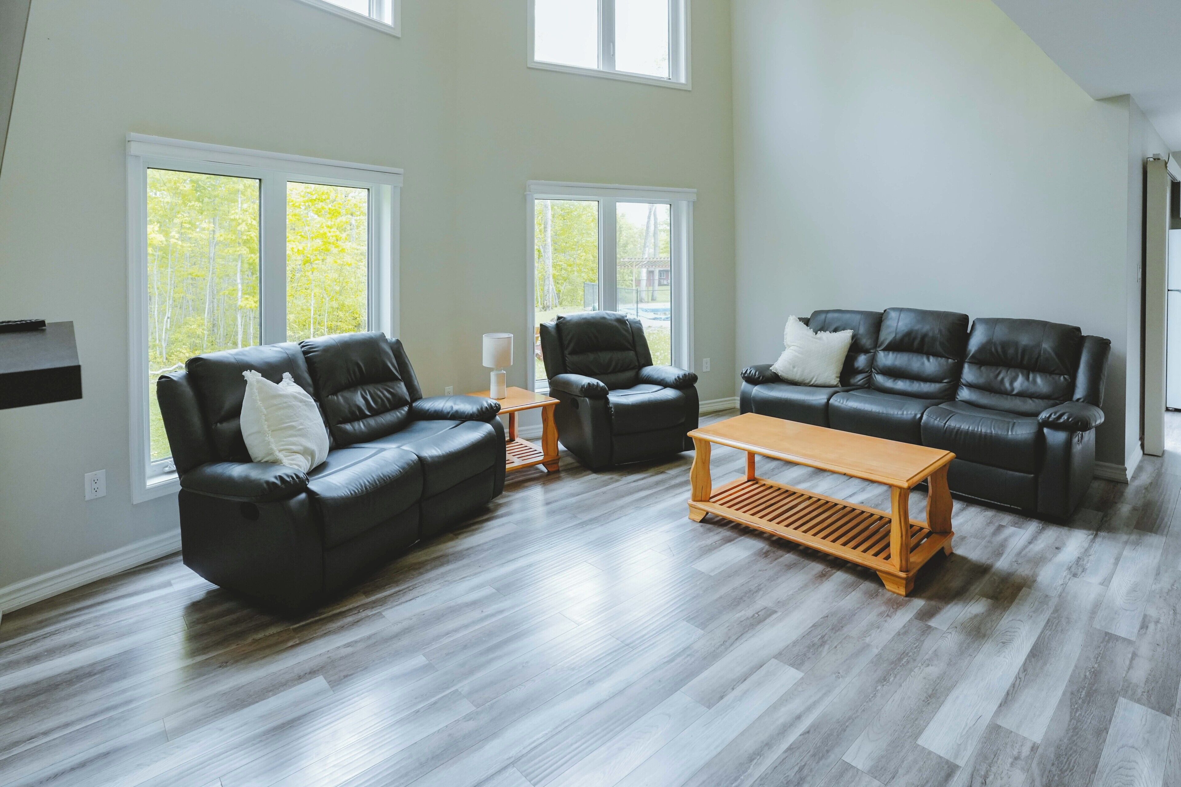 Una sala de estar con dos sofás de cuero negro, una mesa de centro de madera y una lámpara.