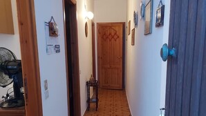 A hallway with patterned flooring, a wooden door, and wall-mounted lights.