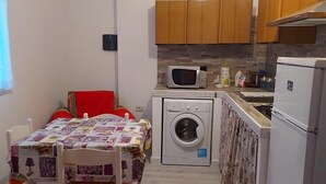 Une cuisine compacte équipée d’un lave-linge, d’un four à micro-ondes et d’un réfrigérateur.