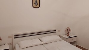 Une chambre à coucher avec un lit, des tables de chevet, une lampe et un tableau accroché au mur.