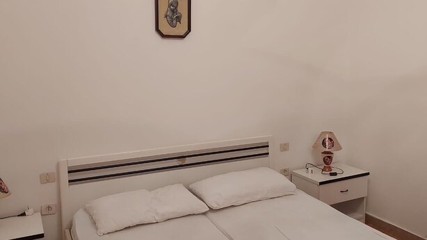 A bedroom with a bed, bedside tables, a lamp, and a wall-mounted picture.