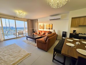 A modern living room with a sofa, coffee table, and dining table set for four.