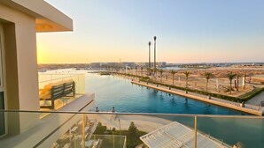 Ein Balkon mit Blick auf einen Yachthafen, ein Schwimmbad und einen Strandbereich.