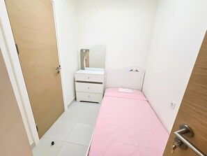 A small bedroom with a single bed, a bedside table, a mirror, and a wardrobe.
