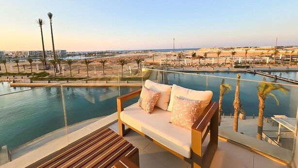 Ein Balkon mit Pool, einer Sitzecke und Blick auf eine Stadtlandschaft.