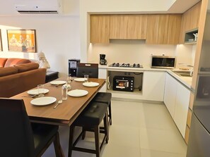 A compact living space with a dining area, kitchenette, and a sofa.