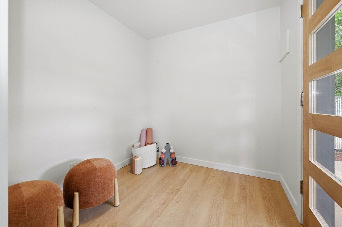 A room with a wooden floor, white walls, a white door, and a window.