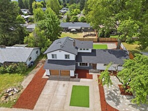 A two-story house with a garage, a front yard with a lawn, and a driveway. - Private Hot Tub, Game Room, Near UO & Autzen (Eugene)