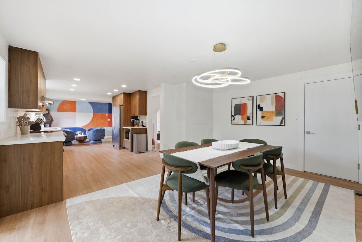 Una cocina moderna con armarios de madera, un comedor con mesa y sillas, y una isla de cocina.