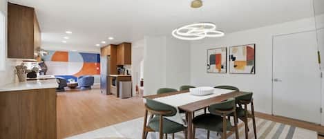 A modern kitchen with wooden cabinets, a dining area with a table and chairs, and a kitchen island.
