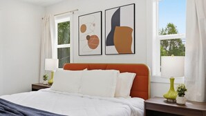A bedroom with a bed, a nightstand, a lamp, and a window.