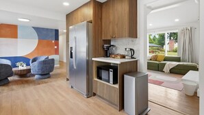 A modern kitchen with wooden cabinets, a stainless steel refrigerator, and a microwave.