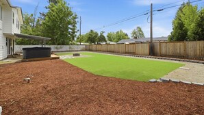 A backyard with a lawn, wooden fence, and a house.
