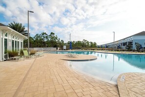 A swimming pool with lounge chairs and a covered area, surrounded by buildings and trees. - Lost Key Retreat Golf and Beach Escape (Pensacola)