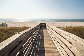 Une promenade en bois qui mène à une plage d’où l’on a une vue dégagée sur l’océan.