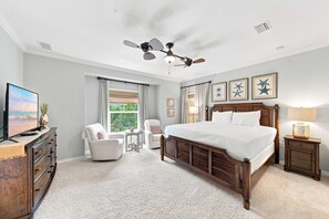 A bedroom with a bed, a chair, a desk, a television, and a ceiling fan. - Lost Key Retreat Golf and Beach Escape (Pensacola)