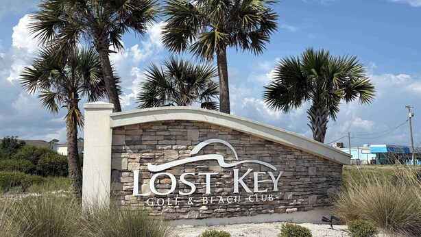 Un mur de pierre sur lequel est inscrit le texte « Lost Key Golf & Beach Club », indiquant le nom de l’établissement.