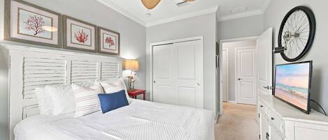 Ein Schlafzimmer mit einem Bett, einem Deckenventilator, gerahmten Kunstwerken, einer Lampe und einem Fahrradrad an der Wand.