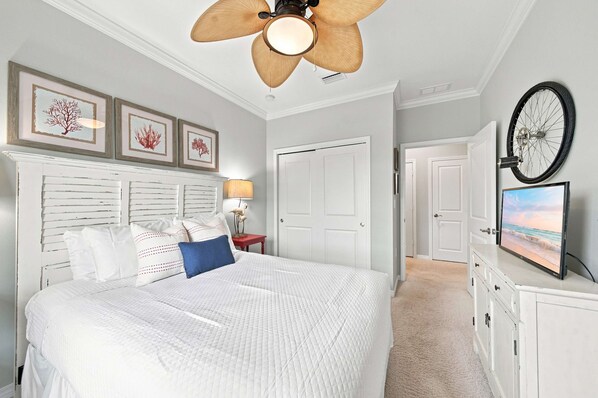 Une chambre à coucher avec un lit, un ventilateur de plafond, des œuvres d’art encadrées, une lampe et une roue de vélo fixée au mur.