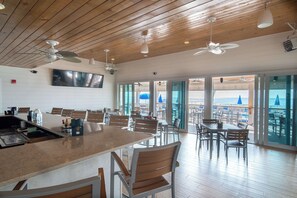 A spacious dining area with a high ceiling, wooden beams, and large windows offering a view of the sea. - Lost Key Retreat Golf and Beach Escape (Pensacola)