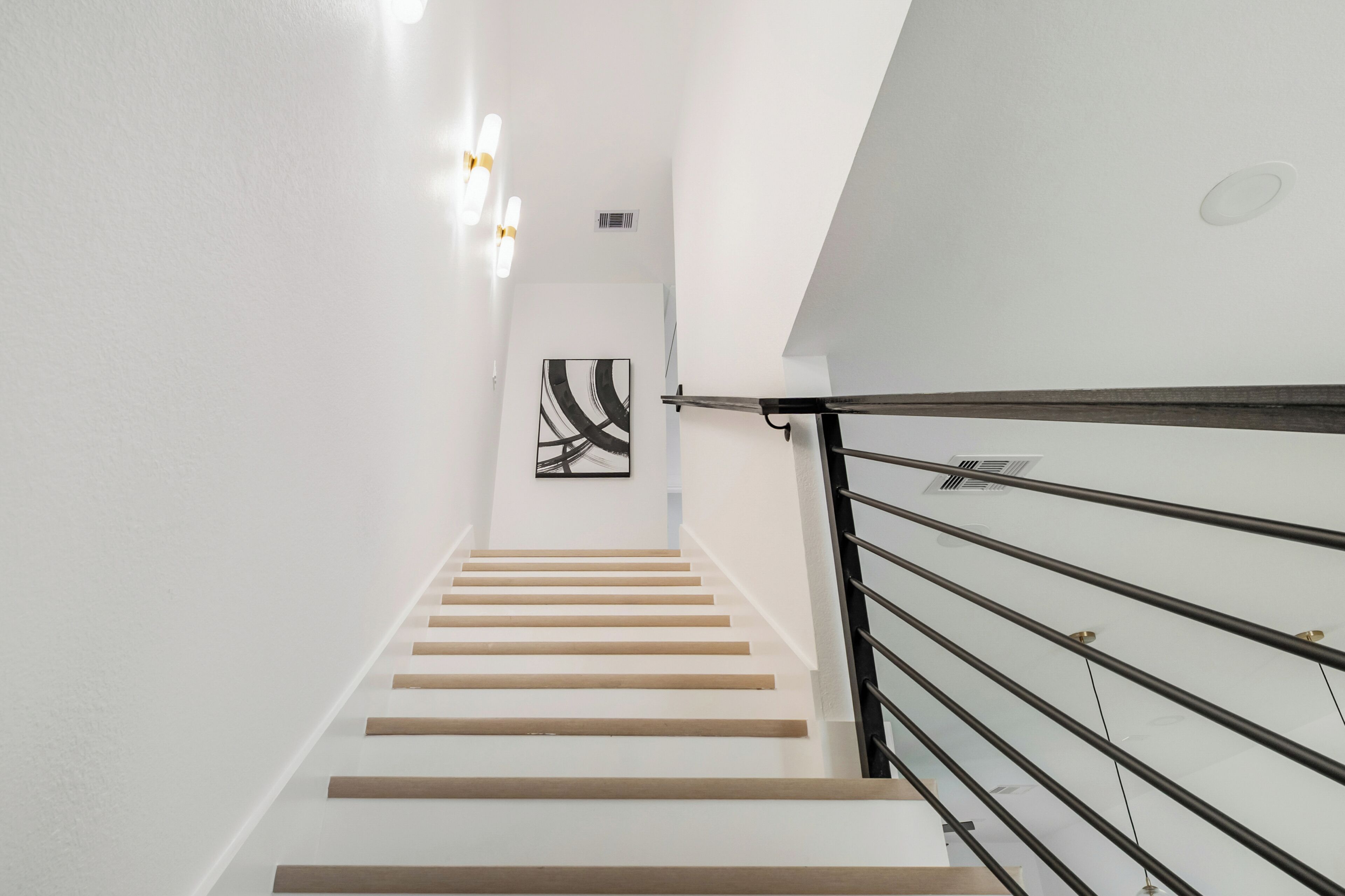 A staircase with a modern design, featuring a wooden handrail and white walls.