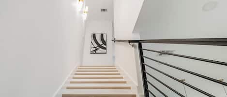 A staircase with a modern design, featuring a wooden handrail and white walls.