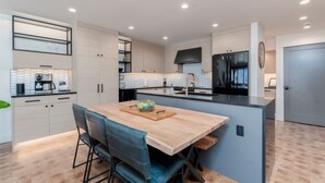 A modern kitchen with a central island, built-in appliances, and a dining area with chairs. - Modern Lakefront Condo F1 + Pool - Wapato Chelan (Manson)