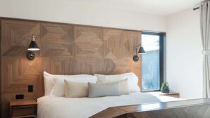 A modern bedroom with a geometric-patterned headboard, a bed with multiple pillows, bedside lamps, and a window with curtains. - Modern Lakefront Condo F1 + Pool - Wapato Chelan (Manson)